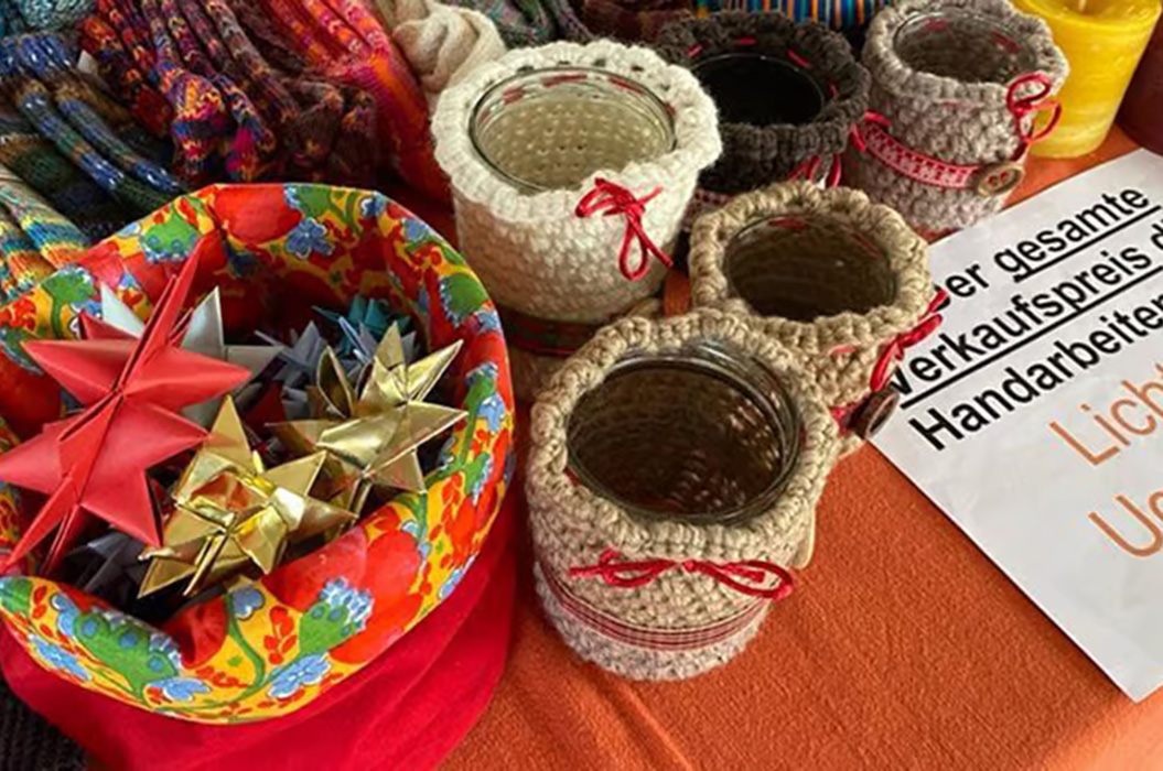 Ein bunter Tisch mit gehäkelten Gläsern, Papiersternen und farbenfroher Schale