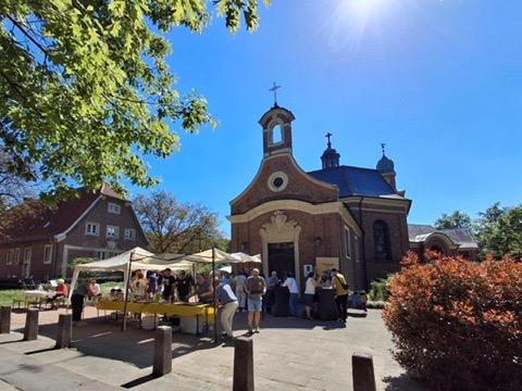 Mehrere Menschen stehen bei sonnigem Wetter lächelnd vor einer roten Backsteinkirche