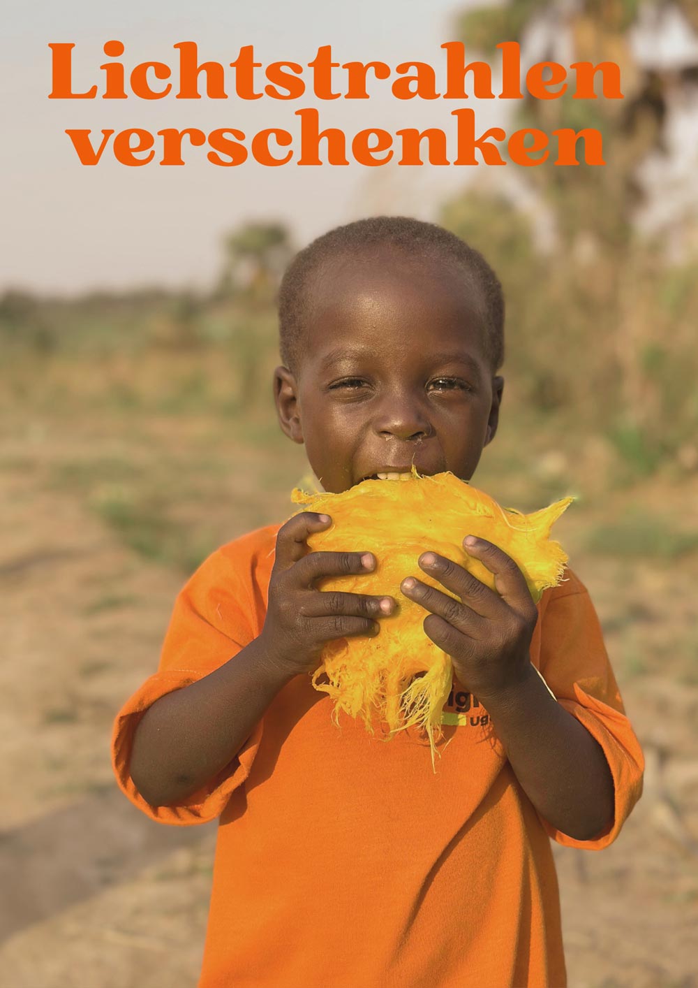 Ein lachender Junge mit kurzem Haar isst eine gelbe Frucht im warmen Sonnenlicht