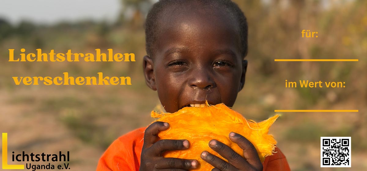 Ein lachender Junge mit dunkler Haut hält ein großes Stück leuchtend orangefarbenes Obst