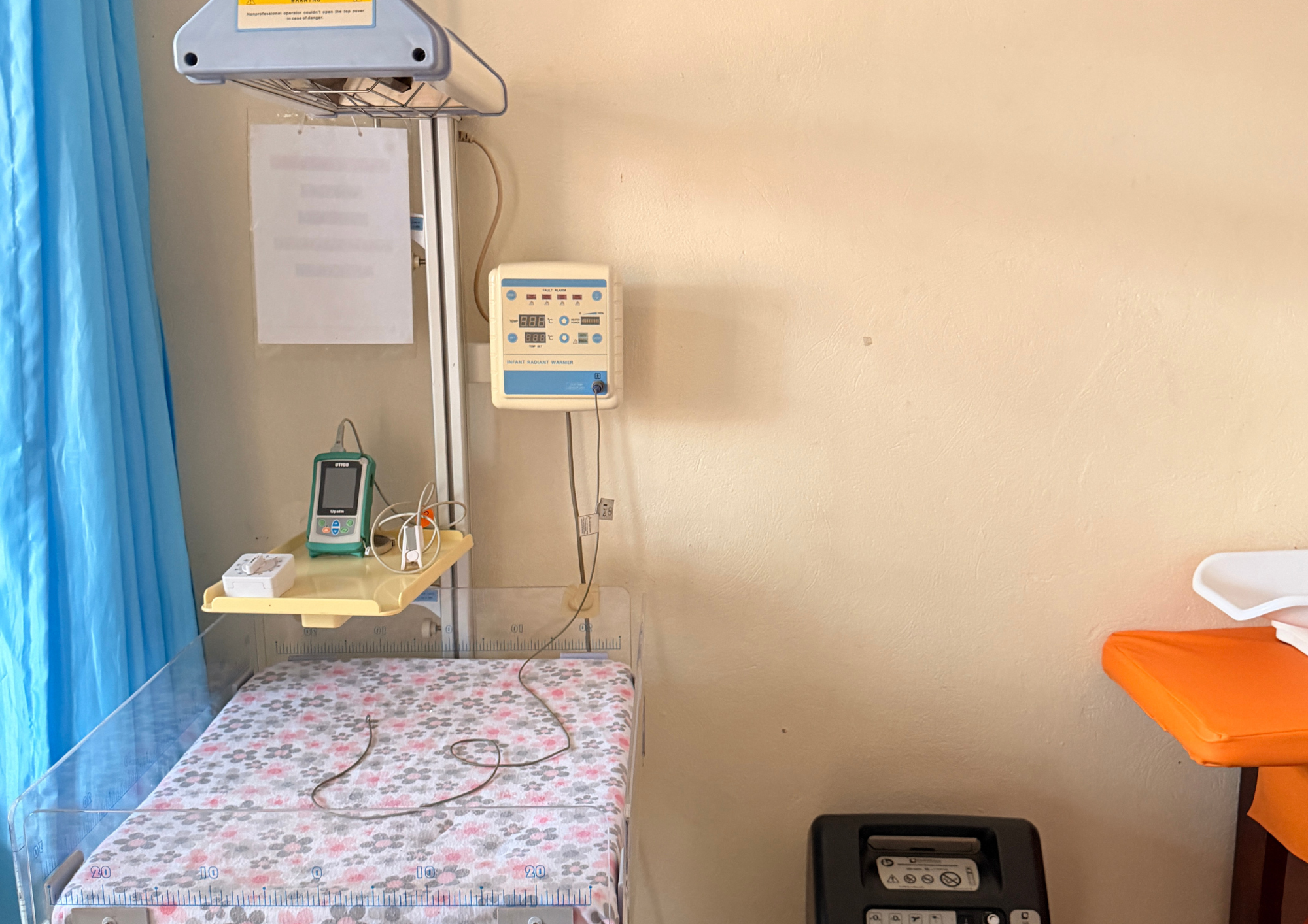 Ein Saeuglingswaermer mit blauen Bedienelementen und gebluemter Matratze im Krankenhaus